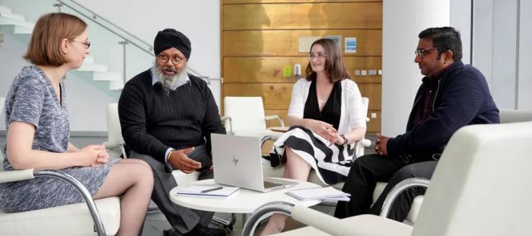 four people sitting around coffee table talking