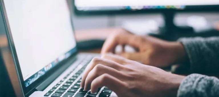 Hands typing on laptop keyboard